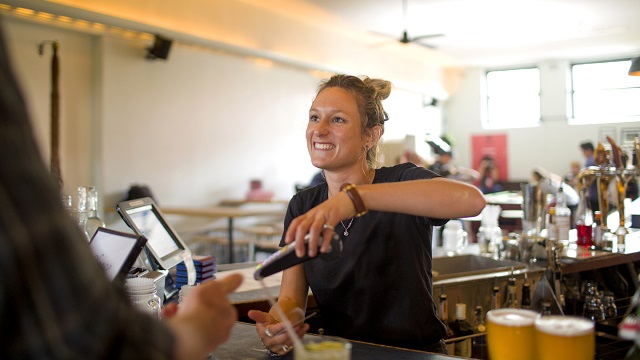 Australian female bartender doing a transaction with pay wave contactless electronic funds transfer